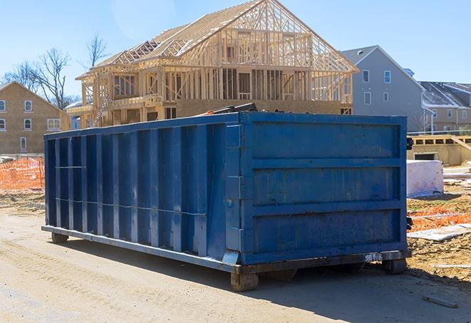 a blue metal dumpster holding trash and recycling bins next to it